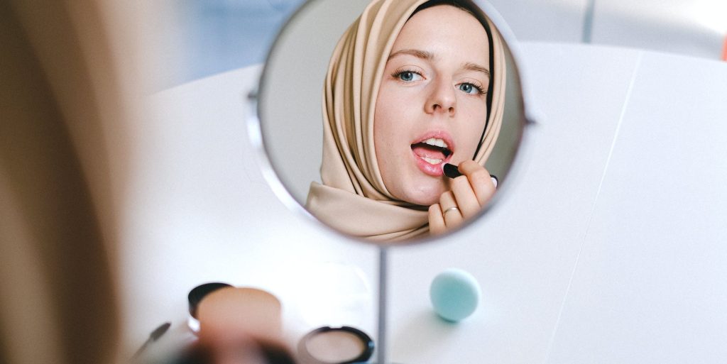 Femme qui applique du maquillage devant un miroir