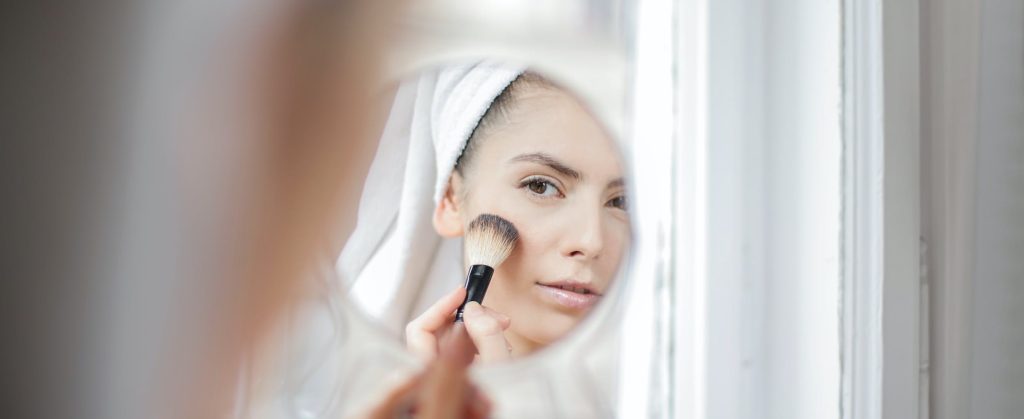 Femme qui se maquille devant un miroir